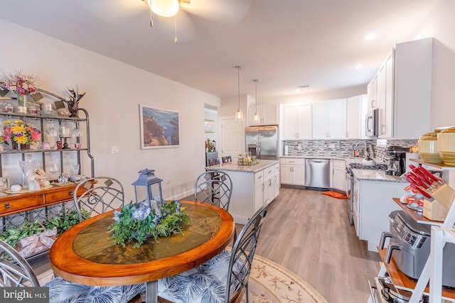 kitchen featuring light stone countertops, appliances with stainless steel finishes, decorative light fixtures, and a kitchen island