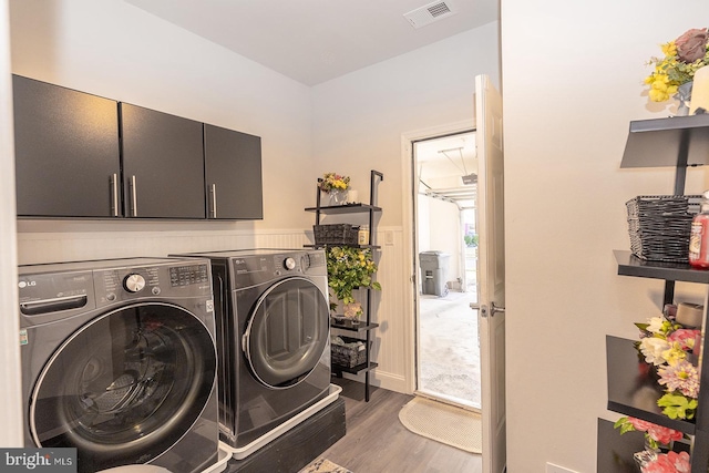 clothes washing area featuring cabinets, dark hardwood / wood-style flooring, and separate washer and dryer