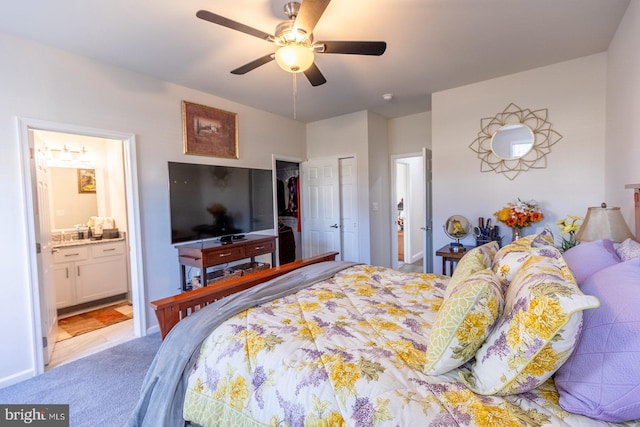 bedroom with ensuite bathroom, ceiling fan, light carpet, and a closet