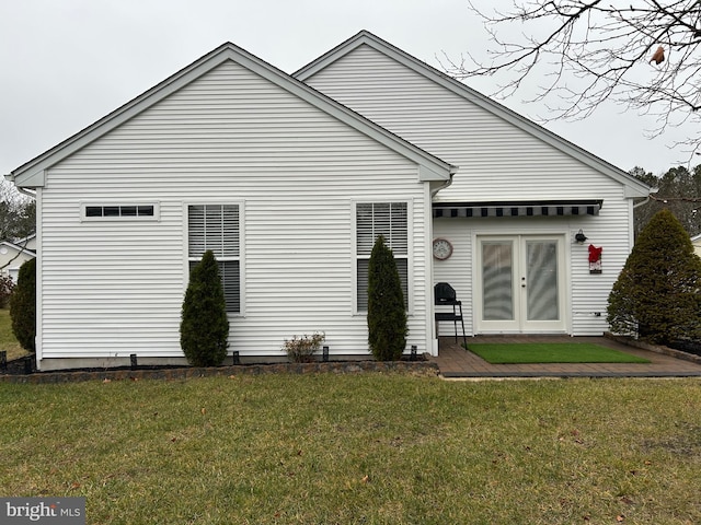 rear view of house featuring french doors and a lawn