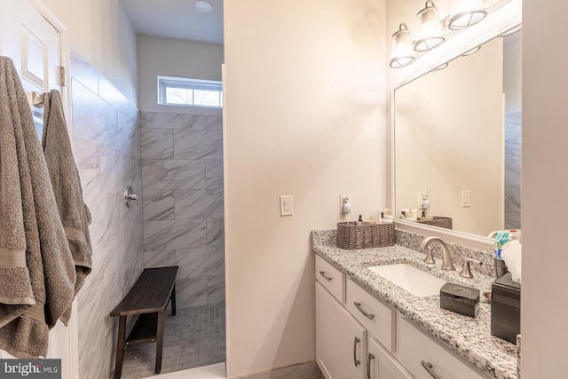 bathroom featuring a tile shower and vanity