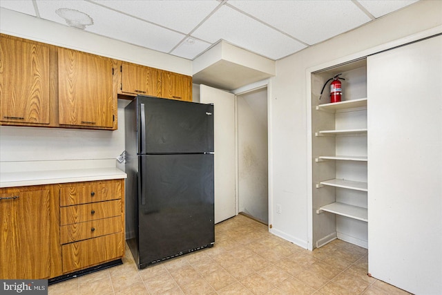 kitchen featuring a paneled ceiling and black fridge