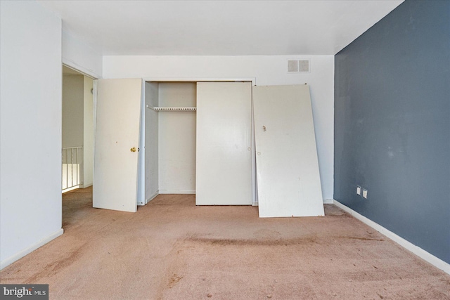 unfurnished bedroom featuring light carpet and a closet