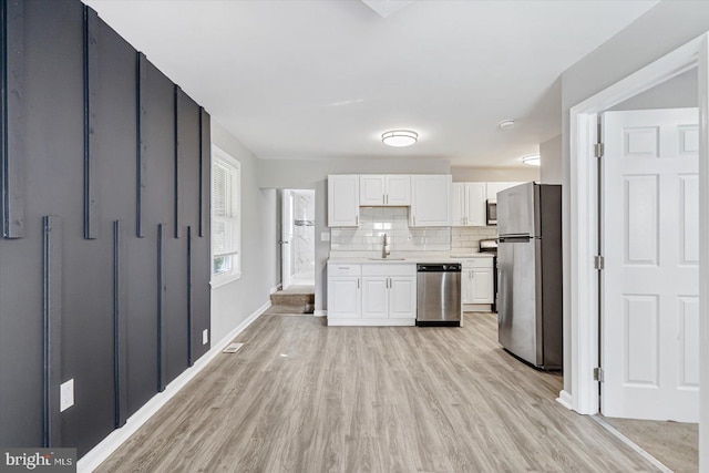 811 Rosedale Ave, Rosedale, MD 21237 - kitchen with white cabinetry, sink, stainless steel appliances, light hardwood / wood-style floors, and decorative backsplash