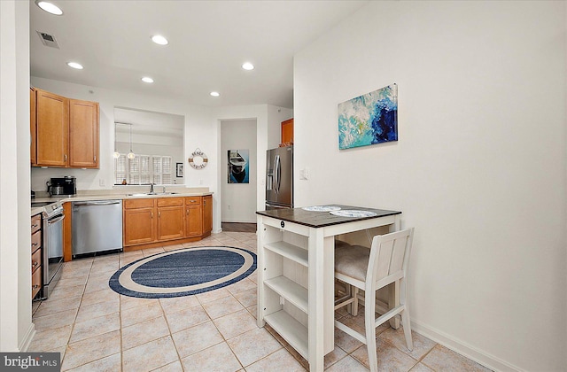 kitchen featuring appliances with stainless steel finishes, a kitchen breakfast bar, sink, light tile patterned floors, and pendant lighting