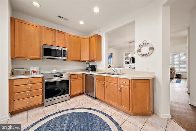 kitchen with sink, light tile patterned flooring, stainless steel appliances, and decorative light fixtures