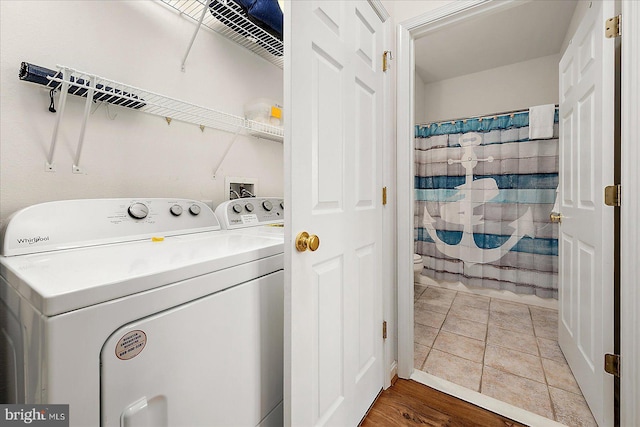 clothes washing area featuring hardwood / wood-style flooring and washing machine and dryer