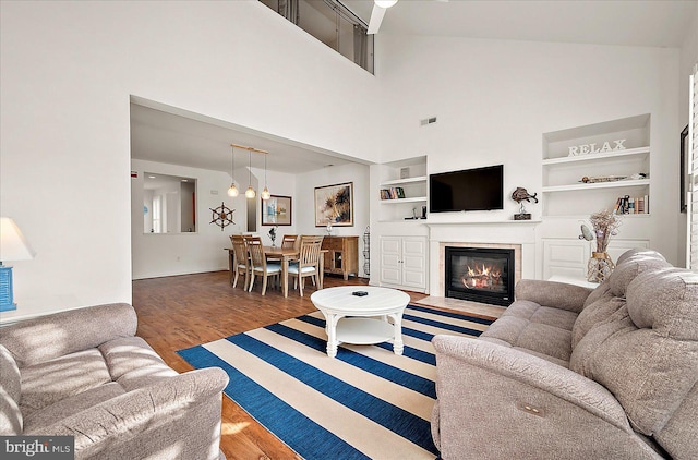 living room with built in shelves, high vaulted ceiling, and dark hardwood / wood-style floors