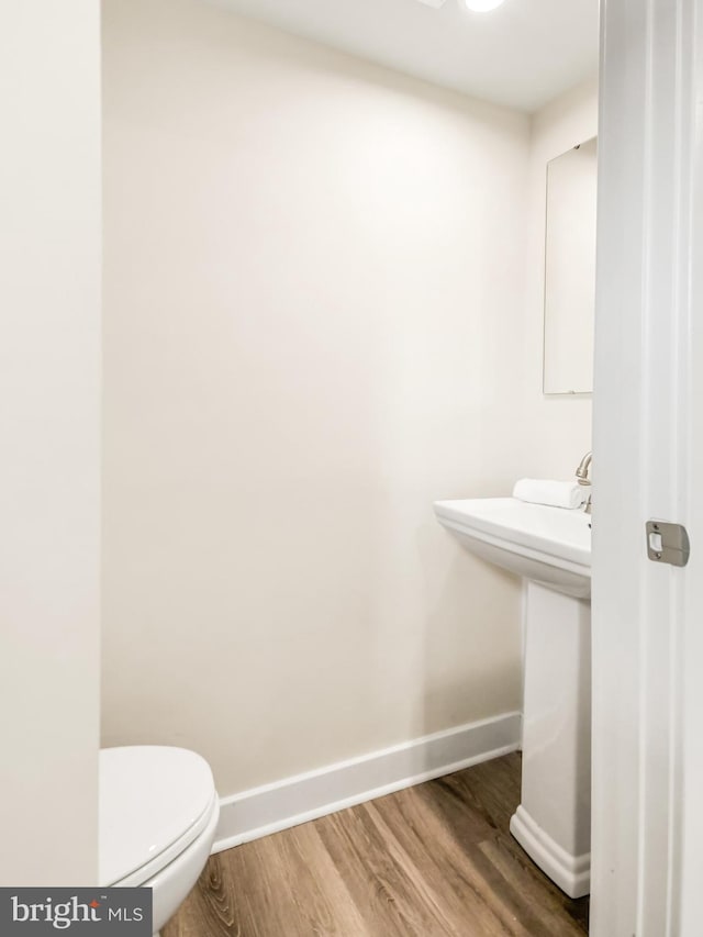 bathroom with wood-type flooring, toilet, and sink