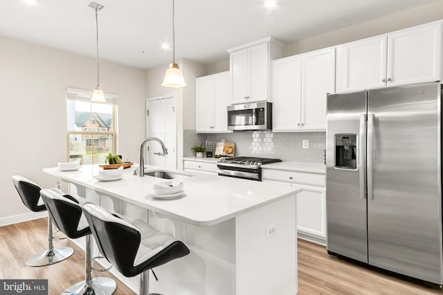 kitchen with stainless steel appliances, white cabinetry, a kitchen island with sink, and sink