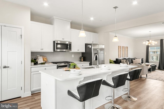 kitchen featuring backsplash, a kitchen island with sink, sink, light hardwood / wood-style floors, and stainless steel appliances