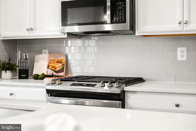 kitchen featuring decorative backsplash, white cabinetry, and appliances with stainless steel finishes