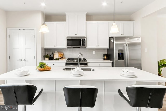 kitchen featuring a kitchen island with sink, pendant lighting, and appliances with stainless steel finishes