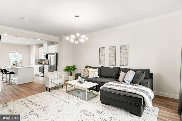 living room featuring light hardwood / wood-style floors, sink, crown molding, and an inviting chandelier