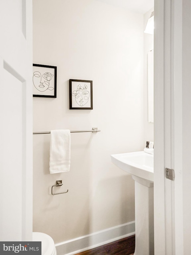 bathroom with wood-type flooring, toilet, and sink