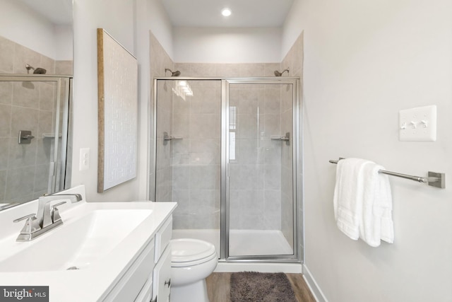 bathroom with vanity, hardwood / wood-style flooring, toilet, and a shower with shower door