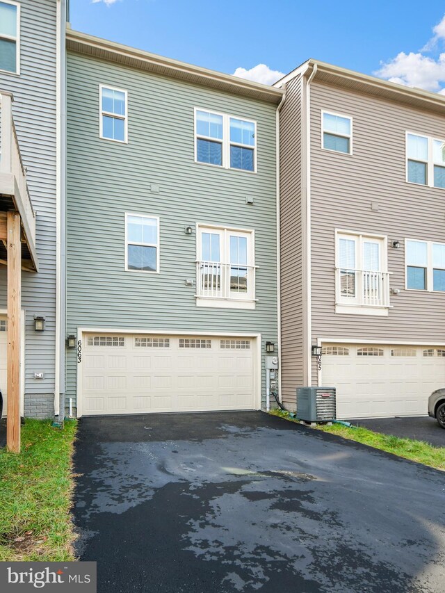 back of property featuring central AC unit and a garage