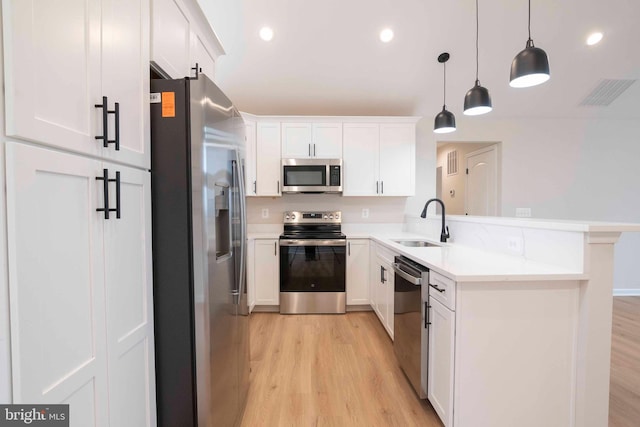 kitchen featuring white cabinetry, hanging light fixtures, stainless steel appliances, and sink