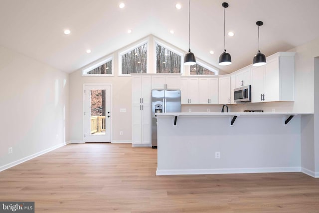 kitchen with white cabinetry, stainless steel appliances, decorative light fixtures, a breakfast bar area, and light wood-type flooring