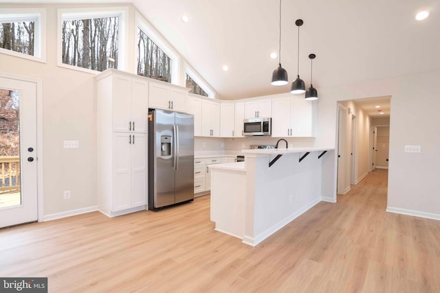 kitchen with white cabinets, appliances with stainless steel finishes, a wealth of natural light, and hanging light fixtures