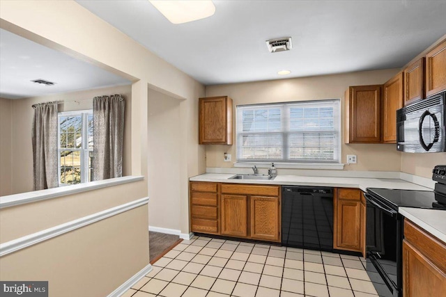 kitchen featuring sink, light tile patterned flooring, and black appliances