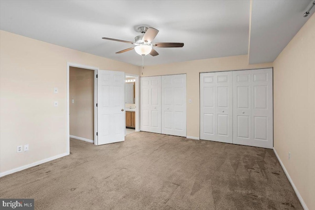 unfurnished bedroom with ceiling fan, light carpet, and multiple closets