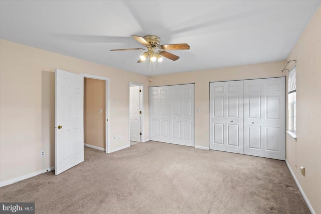 unfurnished bedroom featuring carpet flooring, ceiling fan, and multiple closets