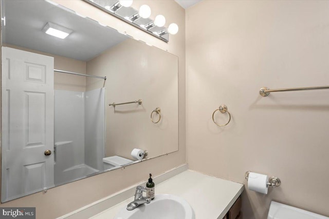 bathroom featuring toilet, vanity, and walk in shower