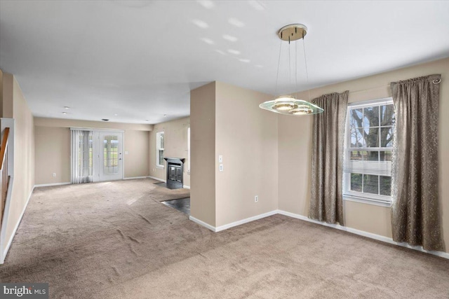 unfurnished living room featuring light carpet, plenty of natural light, and a notable chandelier