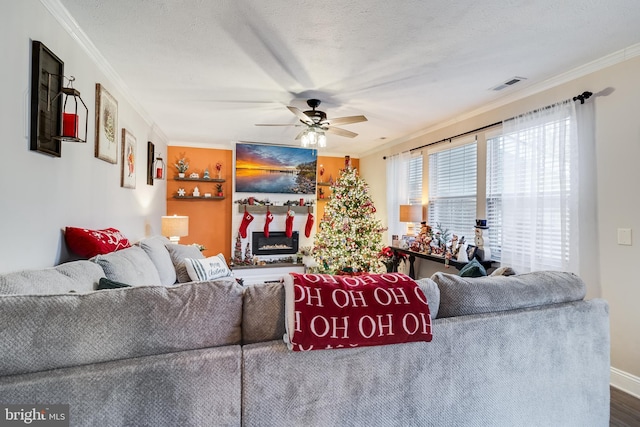 living room featuring ceiling fan, a textured ceiling, and ornamental molding