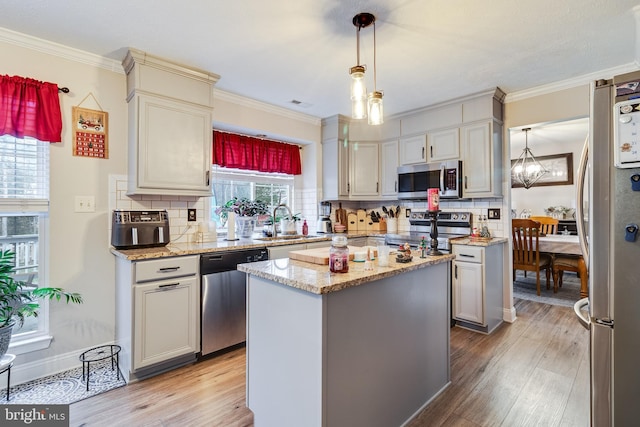 kitchen with a center island, sink, decorative backsplash, decorative light fixtures, and stainless steel appliances