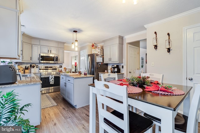 kitchen with hanging light fixtures, backsplash, light hardwood / wood-style floors, a kitchen island, and appliances with stainless steel finishes