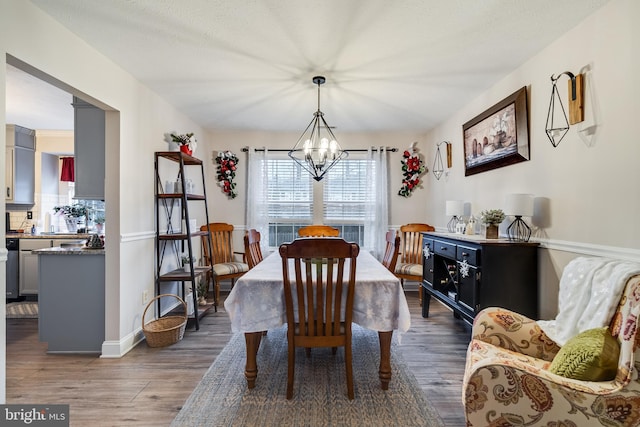 dining space with a textured ceiling, dark hardwood / wood-style flooring, and an inviting chandelier