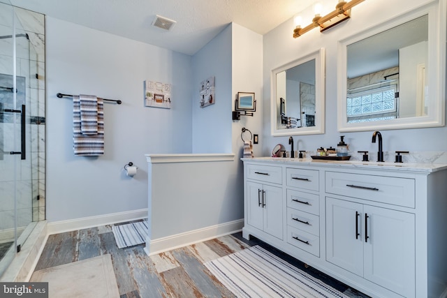 bathroom featuring hardwood / wood-style floors, vanity, a textured ceiling, and walk in shower