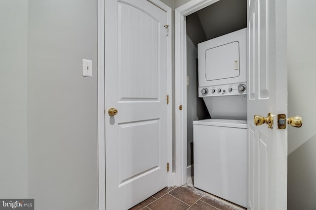 washroom with dark tile patterned floors and stacked washer / drying machine