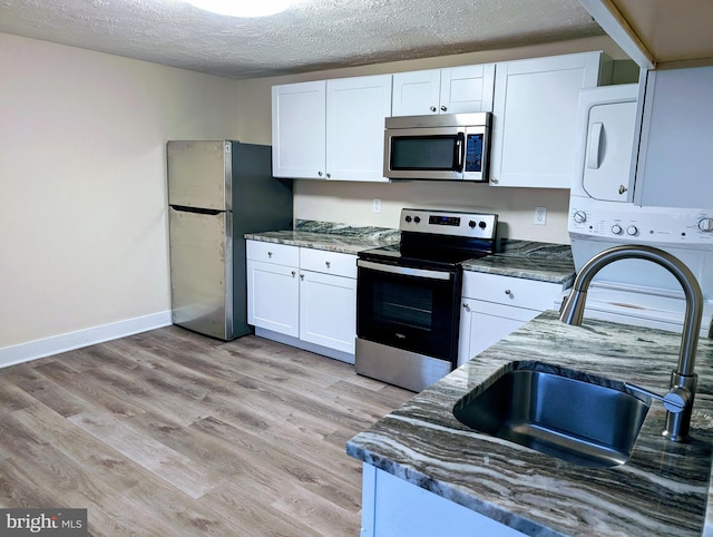 kitchen featuring dark stone counters, white cabinets, and stainless steel appliances