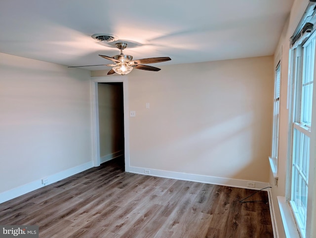 spare room with visible vents, wood finished floors, baseboards, and ceiling fan