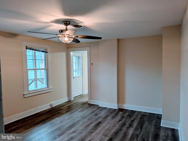 spare room featuring baseboards, ceiling fan, and dark wood-style flooring