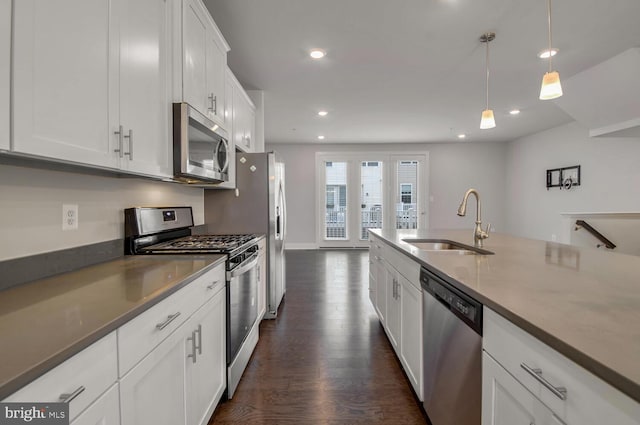 kitchen featuring stainless steel appliances, sink, decorative light fixtures, white cabinetry, and dark hardwood / wood-style flooring