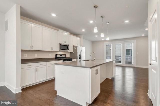 kitchen featuring hanging light fixtures, a center island with sink, white cabinetry, appliances with stainless steel finishes, and sink