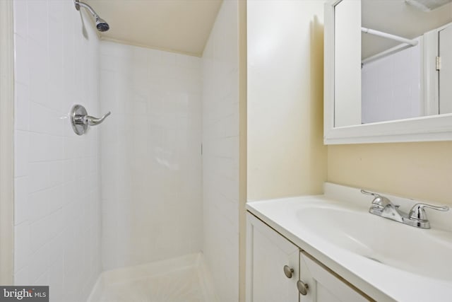 bathroom with tiled shower and vanity