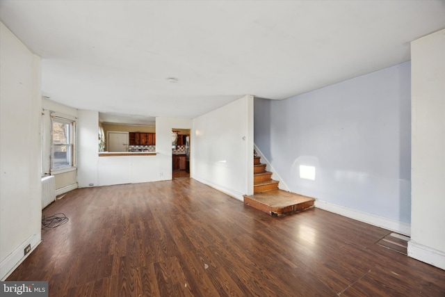 unfurnished living room featuring radiator heating unit and dark wood-type flooring