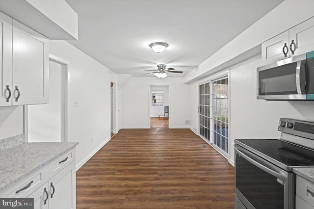 kitchen with white cabinets, appliances with stainless steel finishes, light stone countertops, and dark wood-type flooring