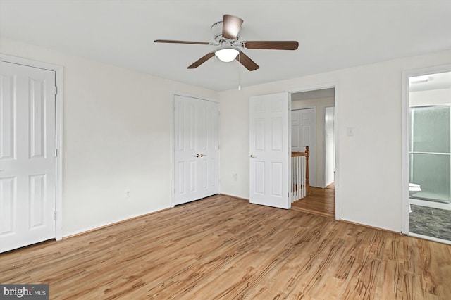 unfurnished bedroom featuring connected bathroom, two closets, light hardwood / wood-style flooring, and ceiling fan