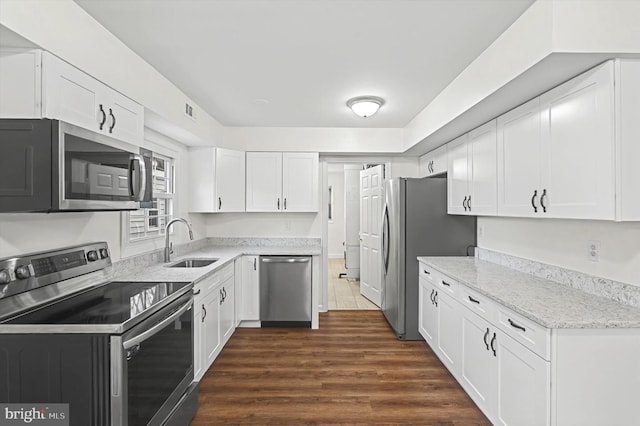 kitchen featuring dark wood-type flooring, white cabinets, sink, light stone countertops, and stainless steel appliances