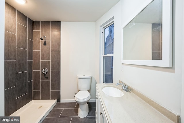 bathroom featuring a tile shower, tile patterned floors, vanity, and toilet