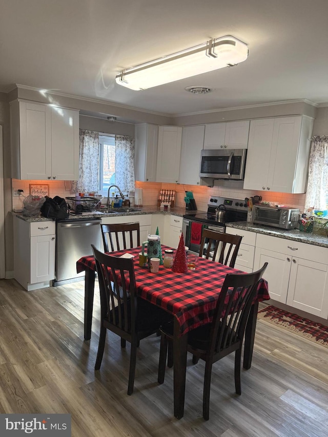 dining room with crown molding, sink, and light wood-type flooring