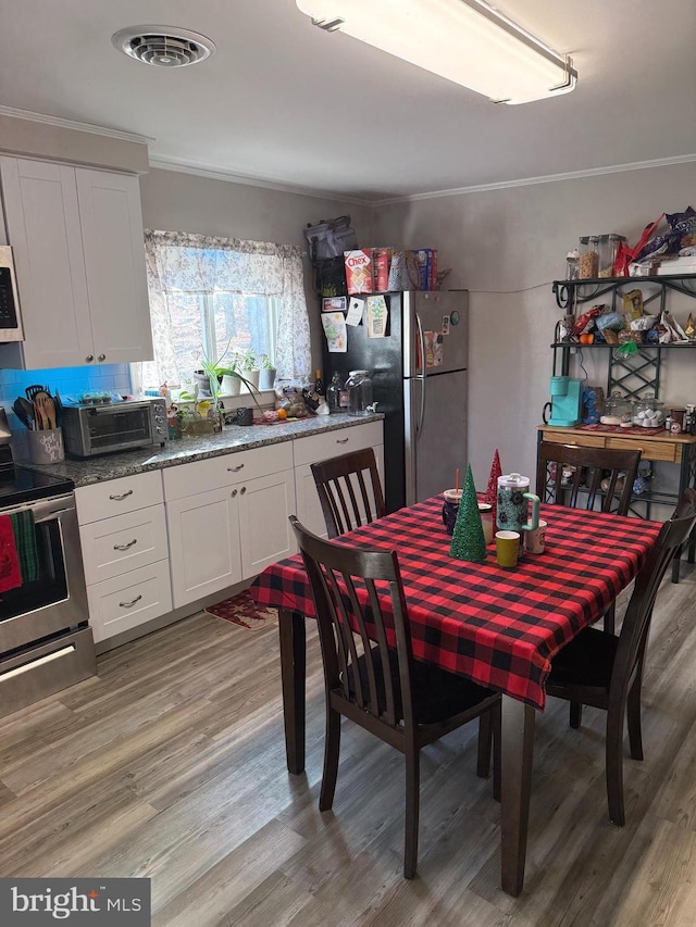 dining room featuring ornamental molding and light wood-type flooring