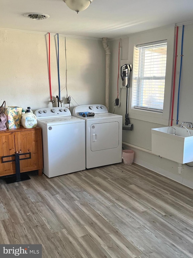 laundry area featuring washer and dryer, light wood-type flooring, cabinets, and sink