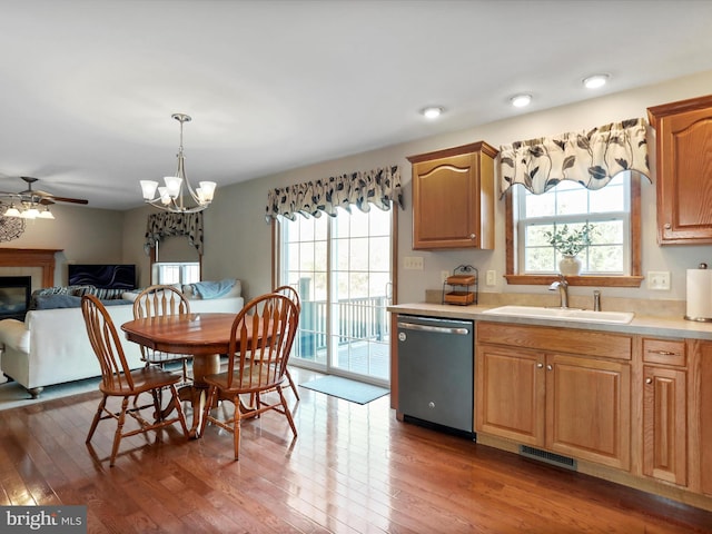 kitchen with dishwasher, sink, hanging light fixtures, dark hardwood / wood-style floors, and ceiling fan with notable chandelier